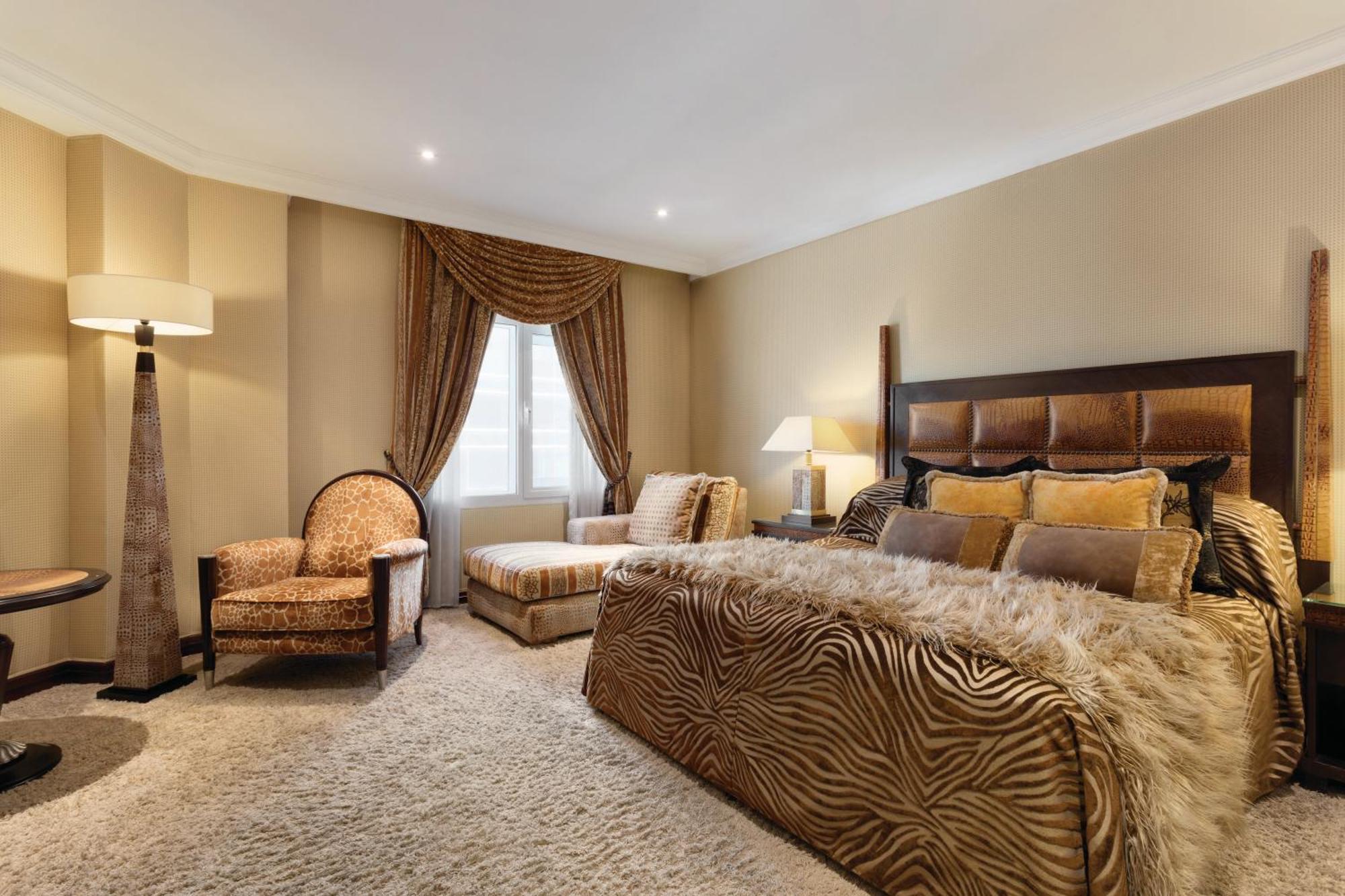 Grand Regency Doha, Trademark Collection By Wyndham Exterior photo The photo shows a stylishly decorated bedroom. The focal point is a large bed dressed in fabrics with a rich, textured appearance, possibly featuring a zebra print or similar design. On either side of the bed, there are small bedside lamps. 

Adjacen